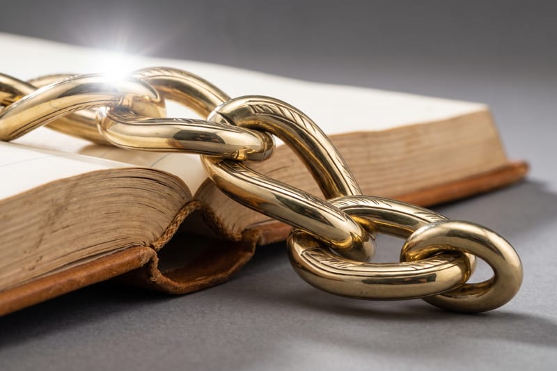 Interlocking brass seal links laid across the gutter of a leather-bound ledger.