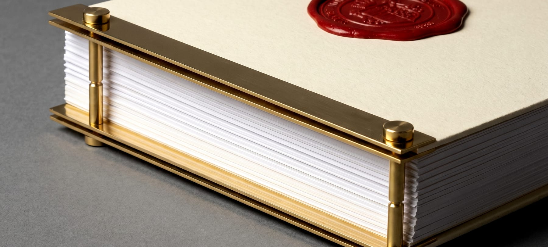 A thick dossier clamped in a brass screw-post binding with a stamped wax seal.