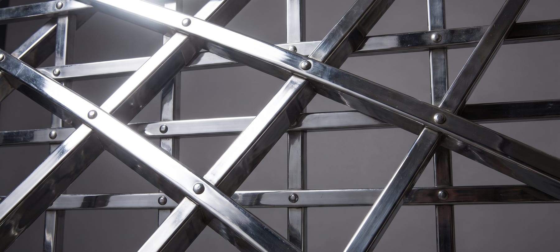 A wrought-iron portcullis grille raked by a single hard light.