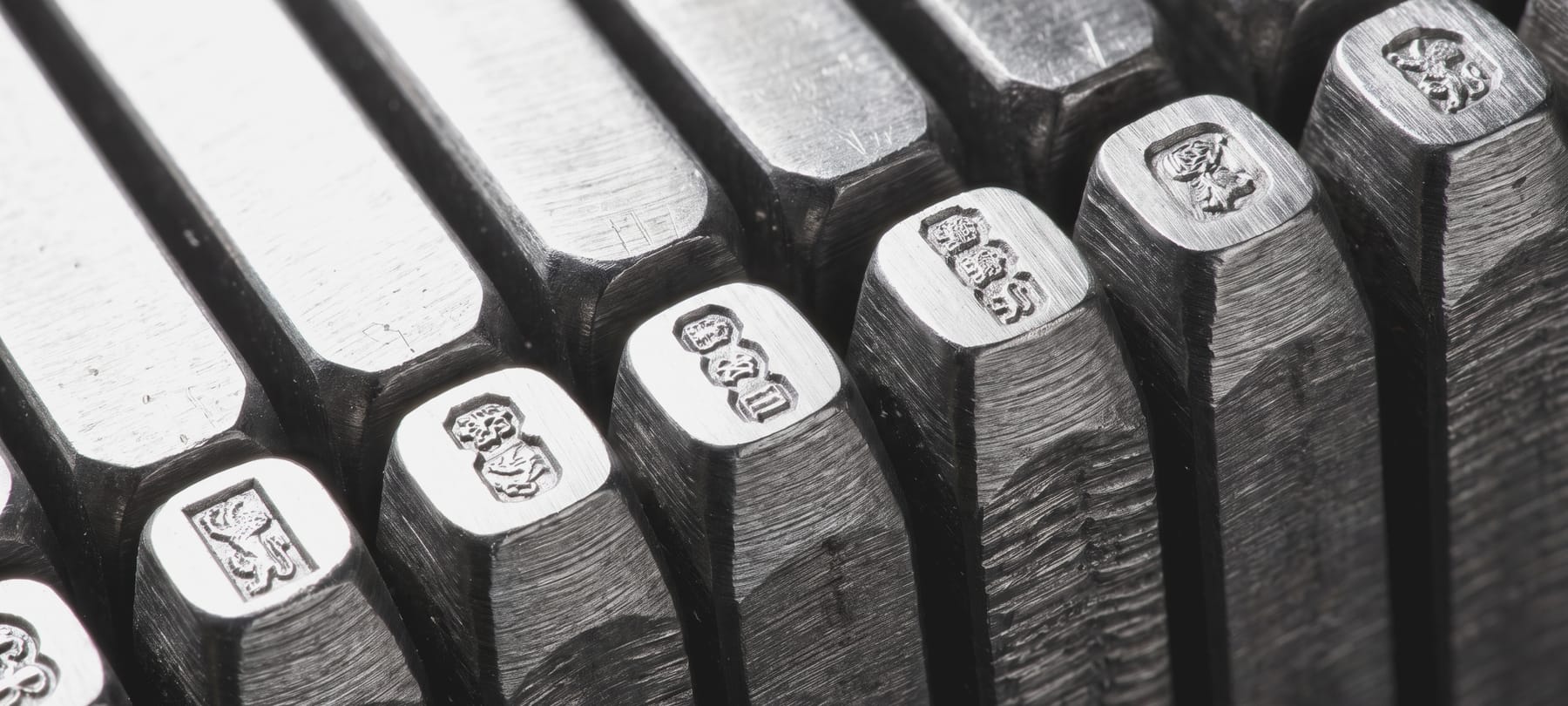 A machined hardened-steel punch die standing upright, its engraved face catching the light.